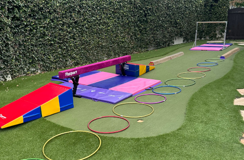 Gymnastics birthday party setup with mats, balance beam, and hoops